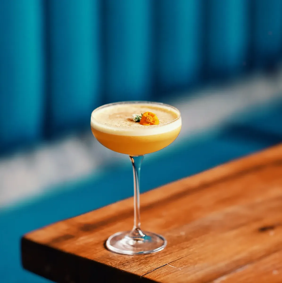 Golden cocktail topped with an edible flower