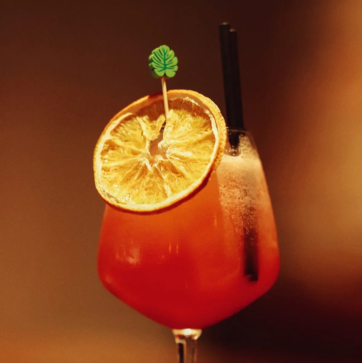Coral spritz with a citrus wheel and straws
