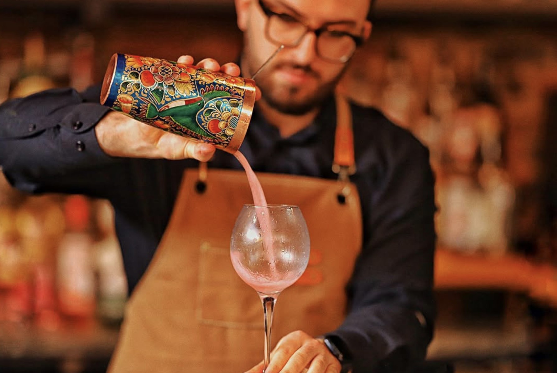 Bartender pouring a cocktail into a chilled glass