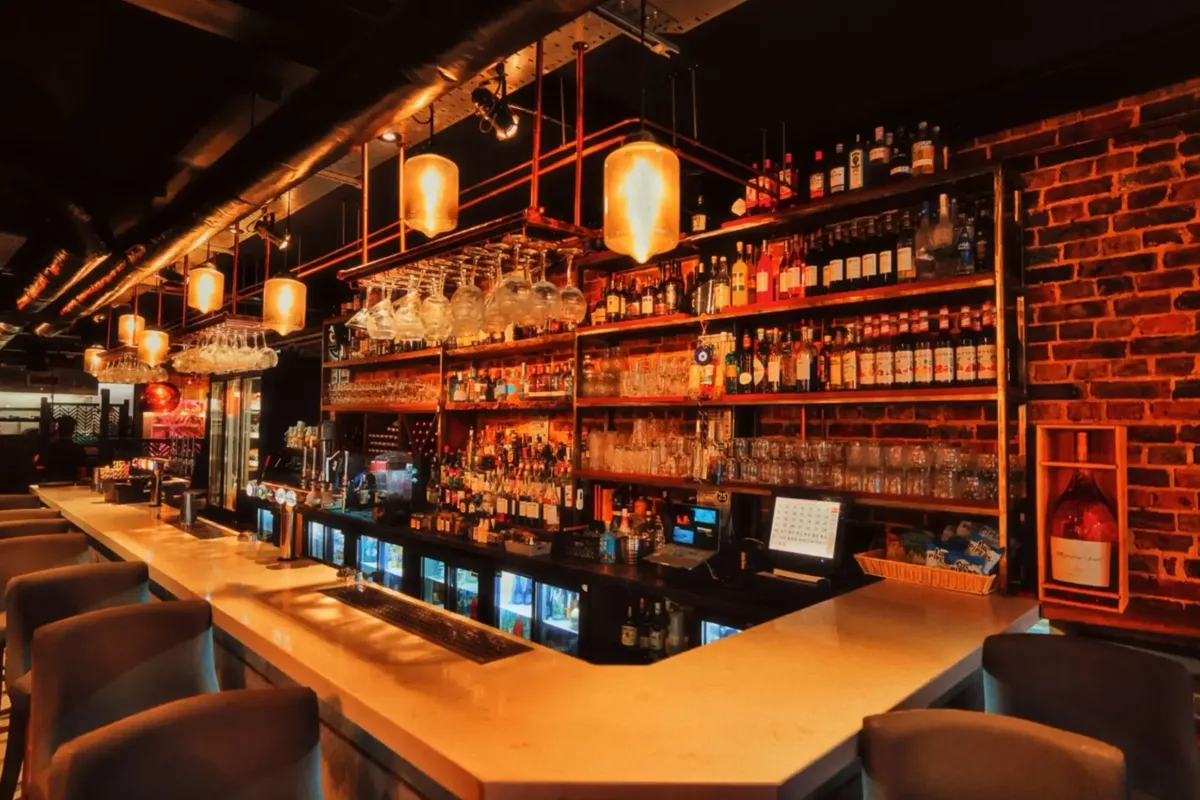 The bar at London Rd. with lit shelves, hanging glassware and draft taps