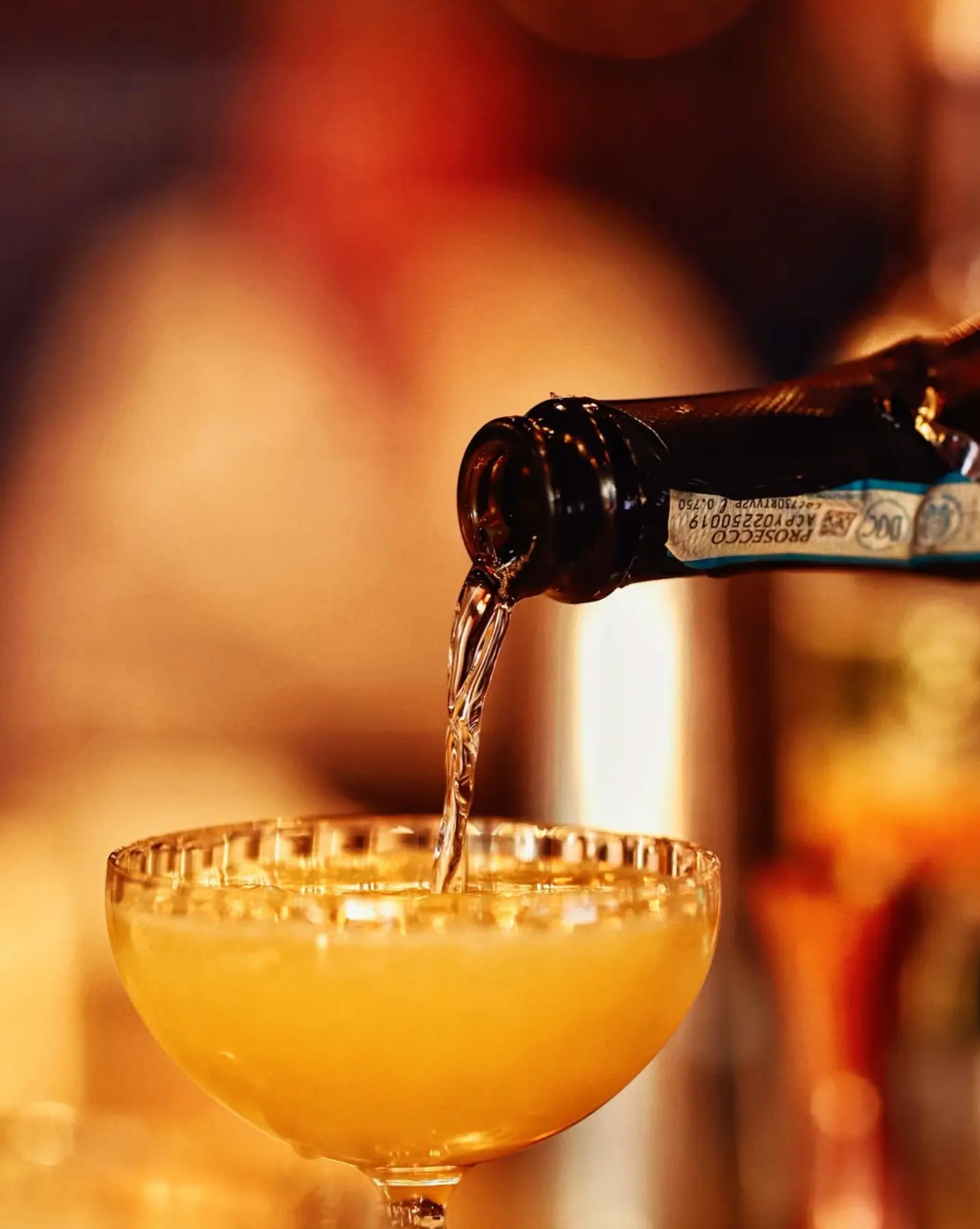 Prosecco being poured into a coupe
