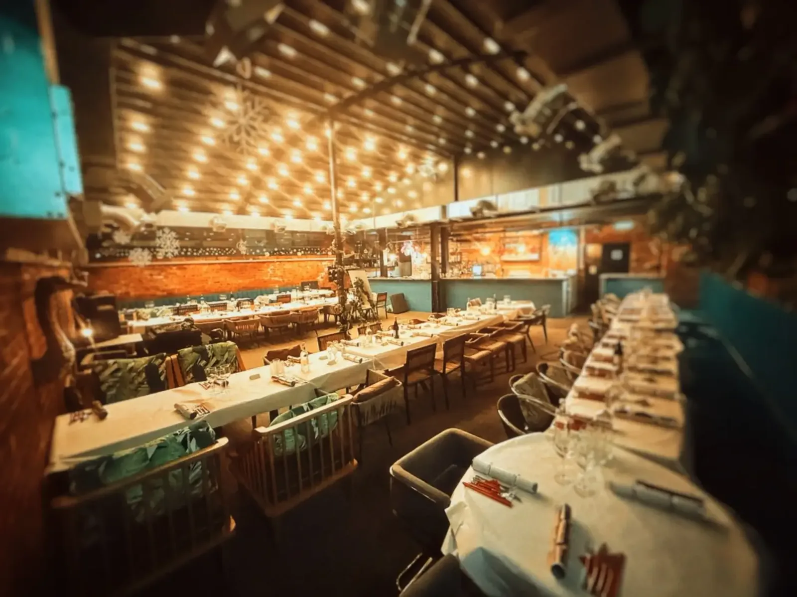 The function room dressed for a private dinner, with banquet tables, glassware and canopy lights