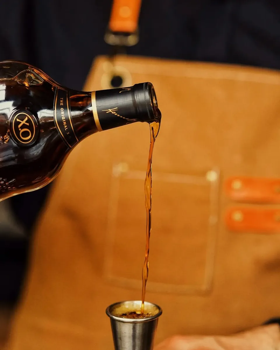Cognac poured into a steel jigger at the bar