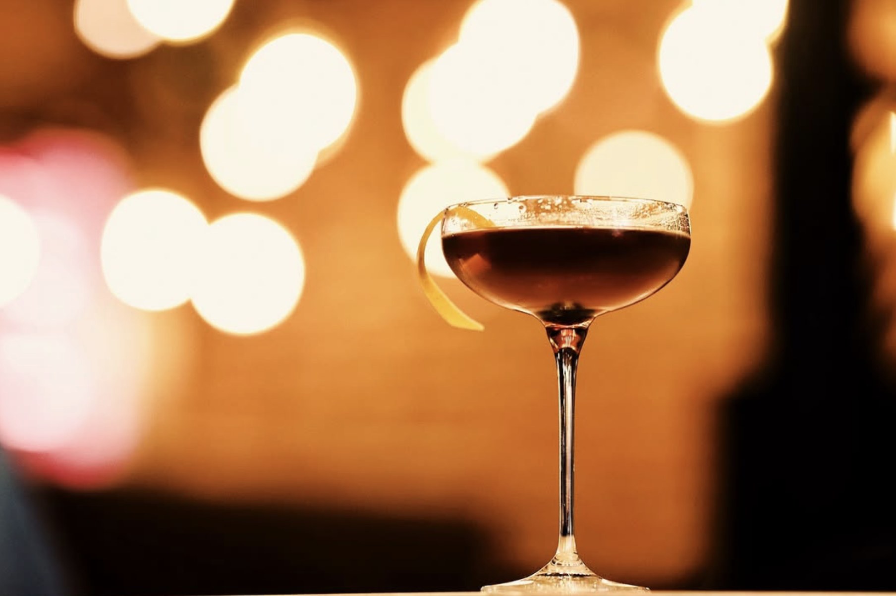 Martini with an orange twist under warm lights