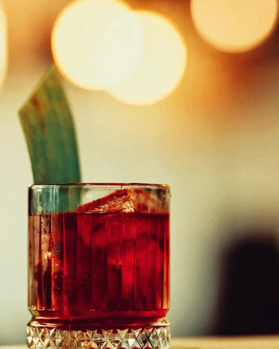 Red cocktail with a pineapple leaf in a cut-crystal glass